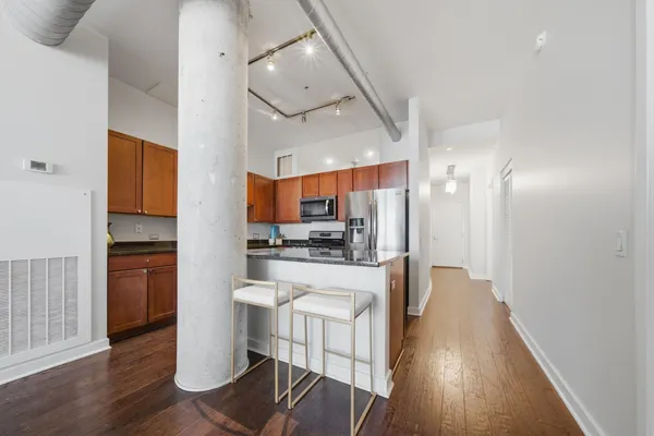 a kitchen with stainless steel appliances a refrigerator a stove a sink dishwasher and a dining table with wooden floor