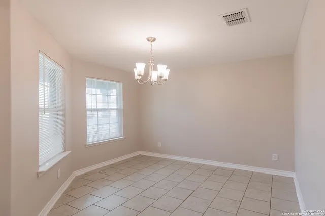 an empty room with chandelier fan and windows