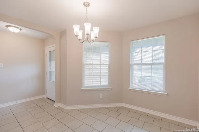an empty room with chandelier fan and windows