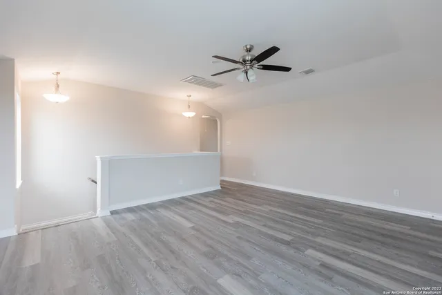 a view of empty room with wooden floor and fan
