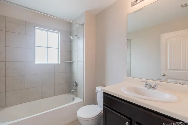 a bathroom with a bathtub shower sink vanity mirror and toilet