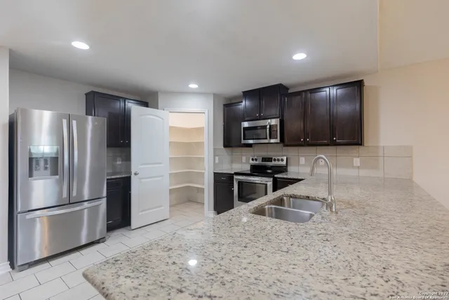 a kitchen with stainless steel appliances granite countertop a refrigerator a stove a sink and a microwave