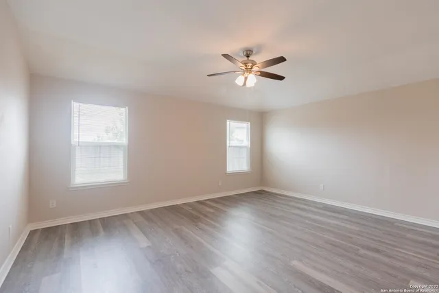 a view of empty room with wooden floor and fan