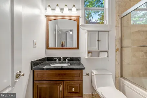 a bathroom with a toilet sink vanity and mirror