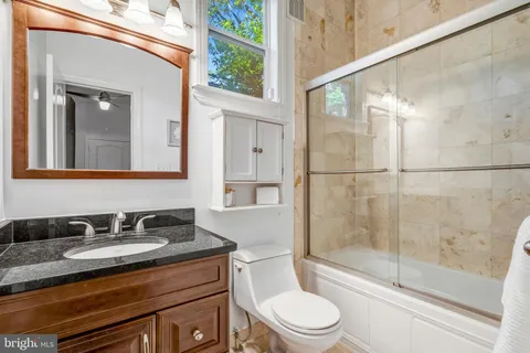 a bathroom with a granite countertop sink toilet and shower