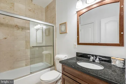 a bathroom with a granite countertop sink toilet a mirror and shower
