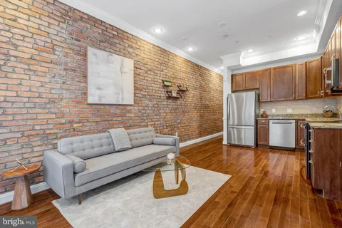 a living room with stainless steel appliances furniture a rug and a kitchen view