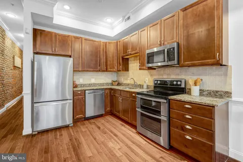 a kitchen with stainless steel appliances granite countertop a refrigerator stove a sink and a microwave oven with wooden floor