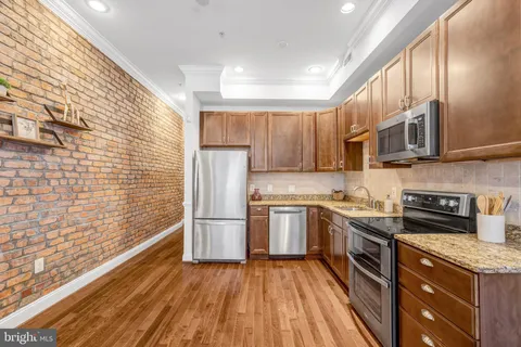 a kitchen with stainless steel appliances granite countertop a stove cabinets and wooden floor
