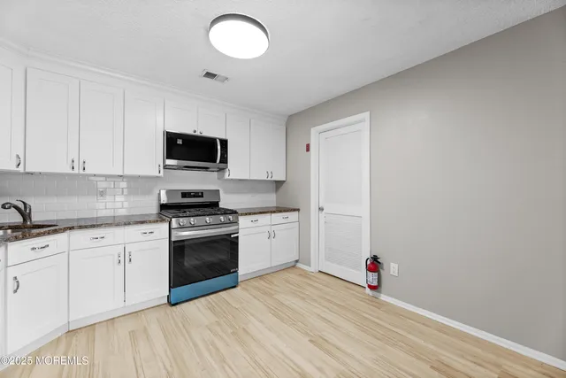 a kitchen with granite countertop a sink cabinets and stainless steel appliances