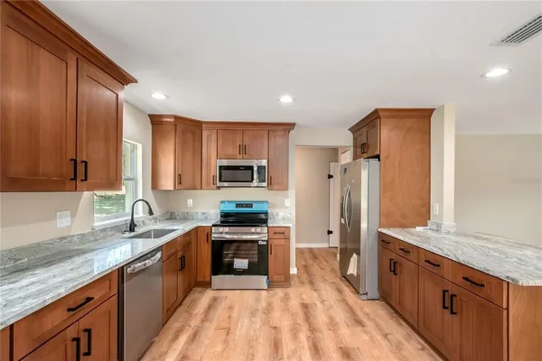 a large kitchen with stainless steel appliances granite countertop a sink stove and refrigerator