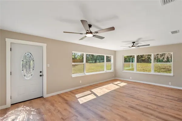 a view of an empty room with a window and wooden floor