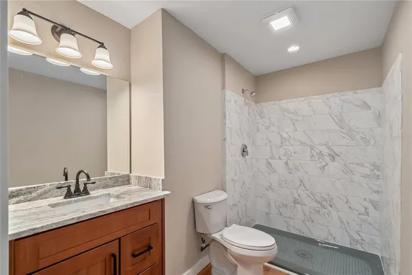 a bathroom with a granite countertop sink a toilet and a mirror