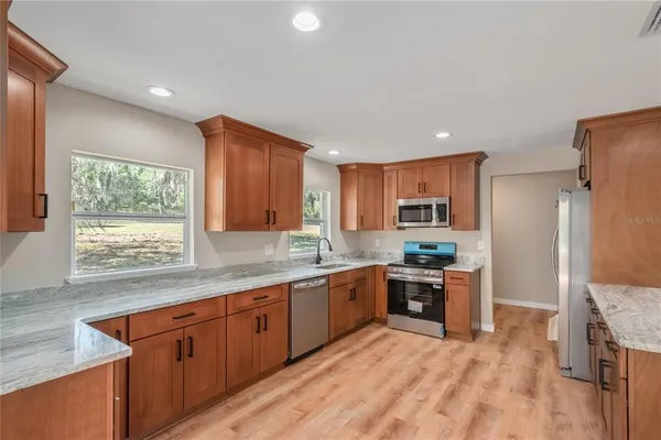 a kitchen with stainless steel appliances granite countertop a stove a sink dishwasher and a refrigerator