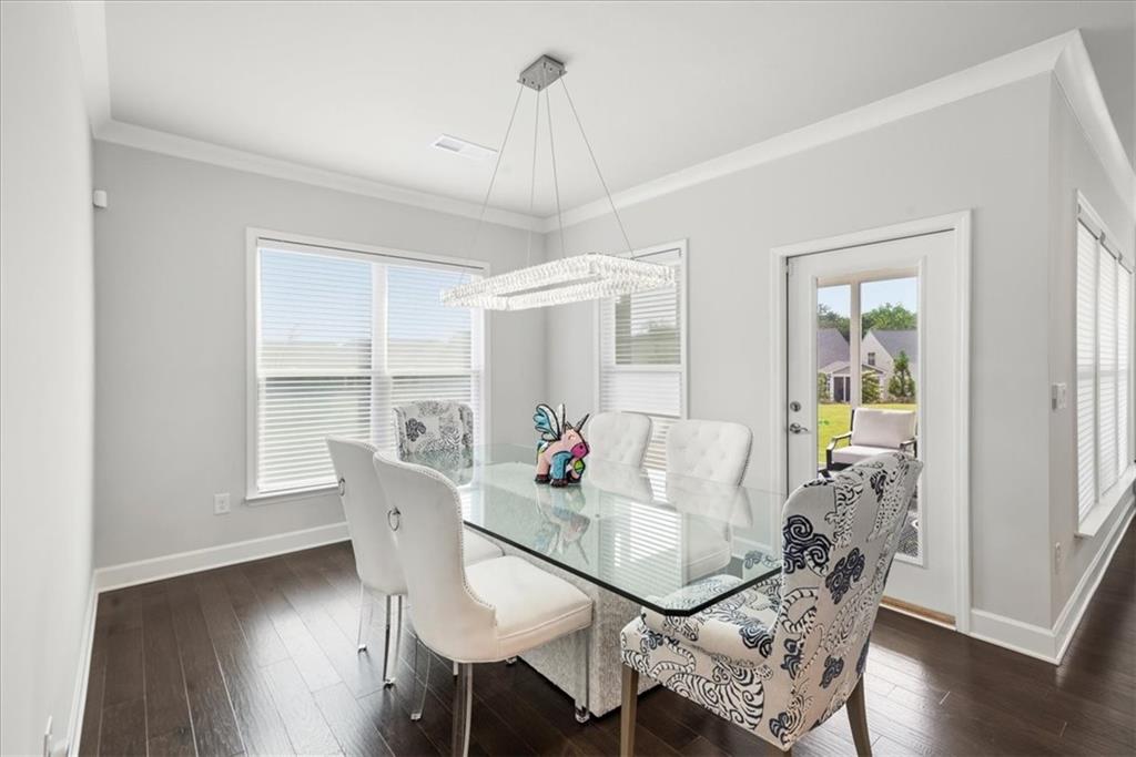 2457 Naples Street Hoschton, GA 30548 - Photo 14 of 41 a dining room with furniture a chandelier and wooden floor