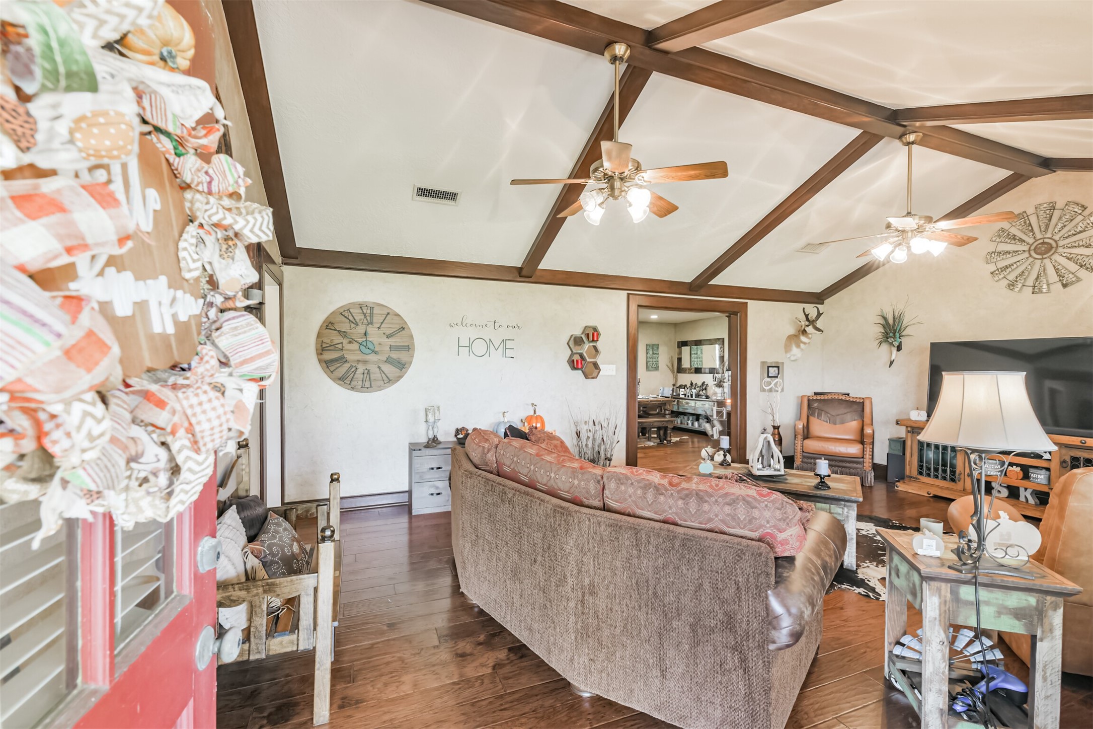 307 West Hufsmith Road Tomball, TX 77375 - Photo 7 of 44 Charming living room with rustic beams, cozy seating, and warm hardwood floors. The space is inviting and perfect for relaxation, with tasteful decor and a welcoming ambiance.