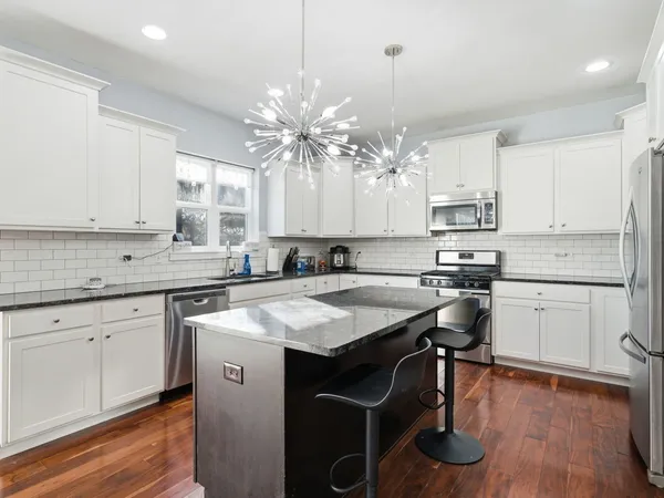 a kitchen with a center island appliances cabinets and a large window