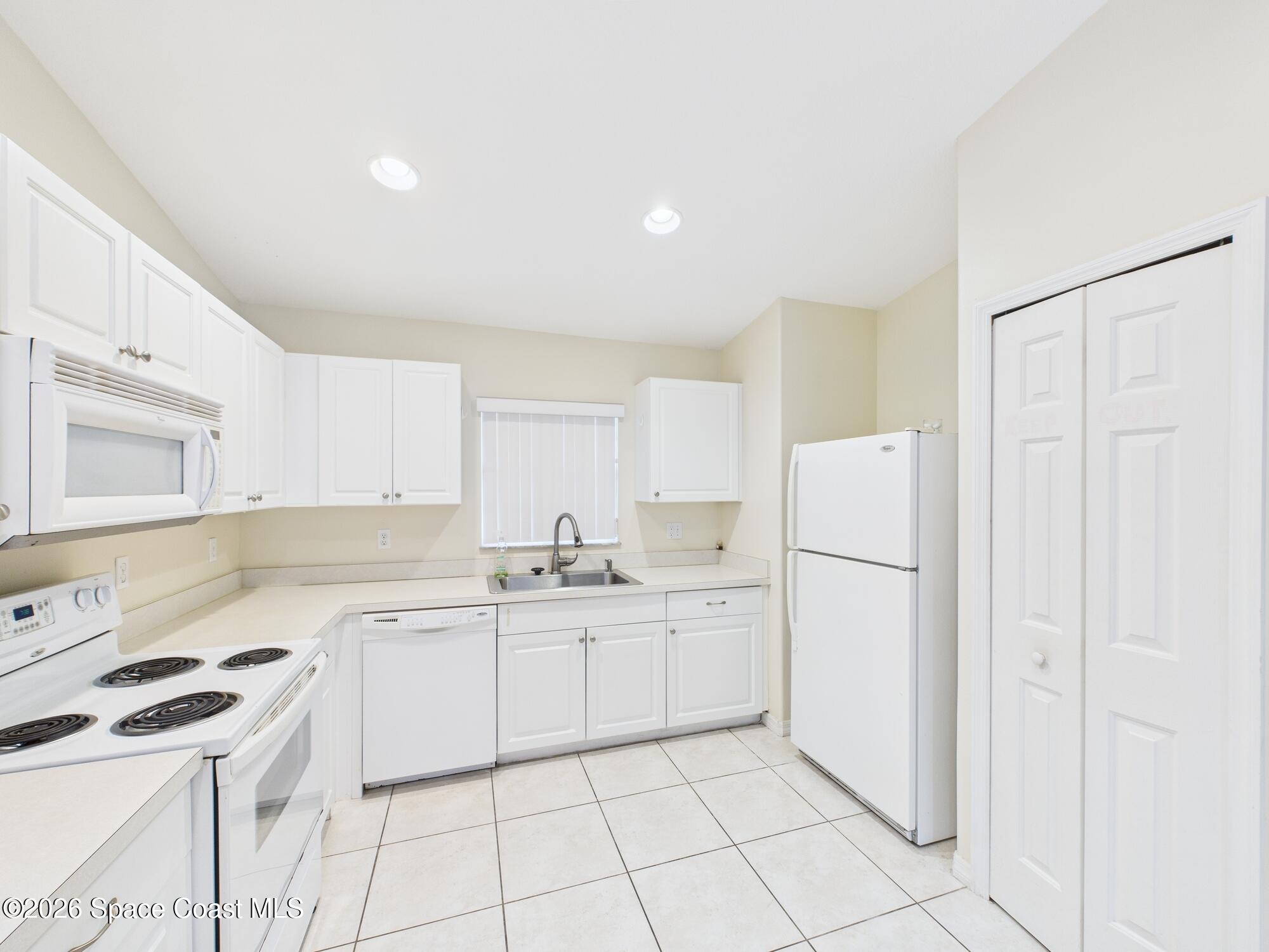 131 Maggie Way Sebastian, FL 32958 - Photo 4 of 19 a kitchen with white cabinets and white appliances
