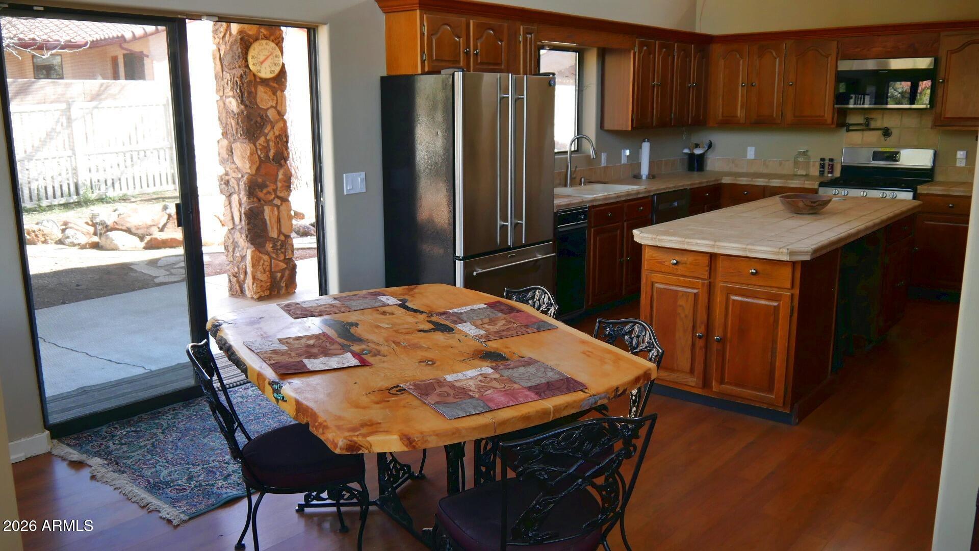 60 Rio Verde Circle Sedona, AZ 86351 - Photo 7 of 28 a kitchen with stainless steel appliances granite countertop a stove a refrigerator a sink a dining table and chairs with wooden floor