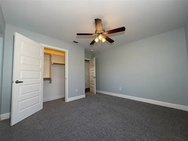 an empty room with closet and a ceiling fan