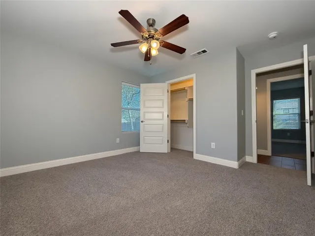 an empty room with closet and ceiling fan
