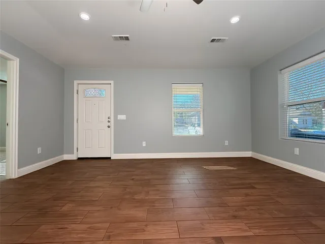 a view of an empty room with window and wooden floor