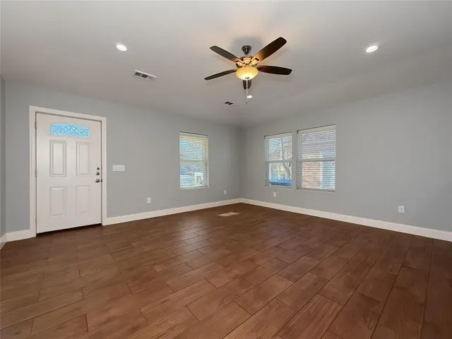 a view of an empty room with window and wooden floor
