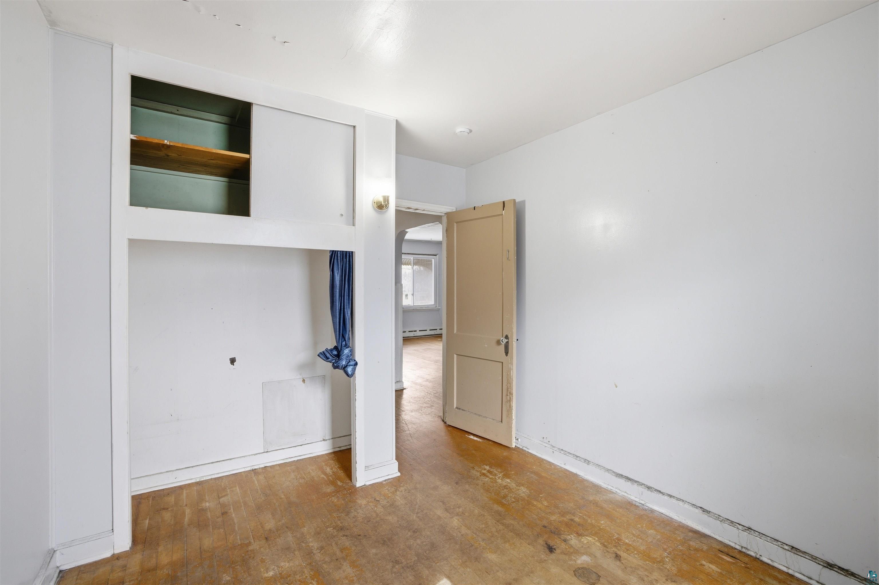 726 Summit Street Eveleth, MN 55734 - Photo 12 of 29 Unfurnished bedroom featuring hardwood / wood-style flooring, a closet, and arched walkways