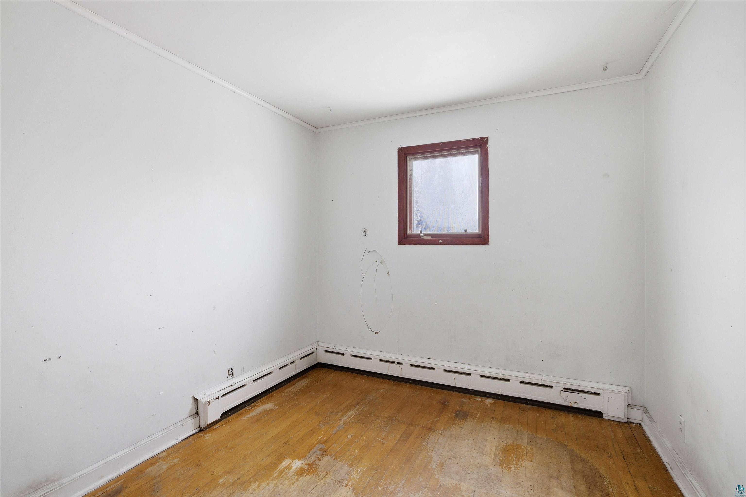 726 Summit Street Eveleth, MN 55734 - Photo 13 of 29 Unfurnished room featuring light wood-style floors, ornamental molding, and baseboard heating