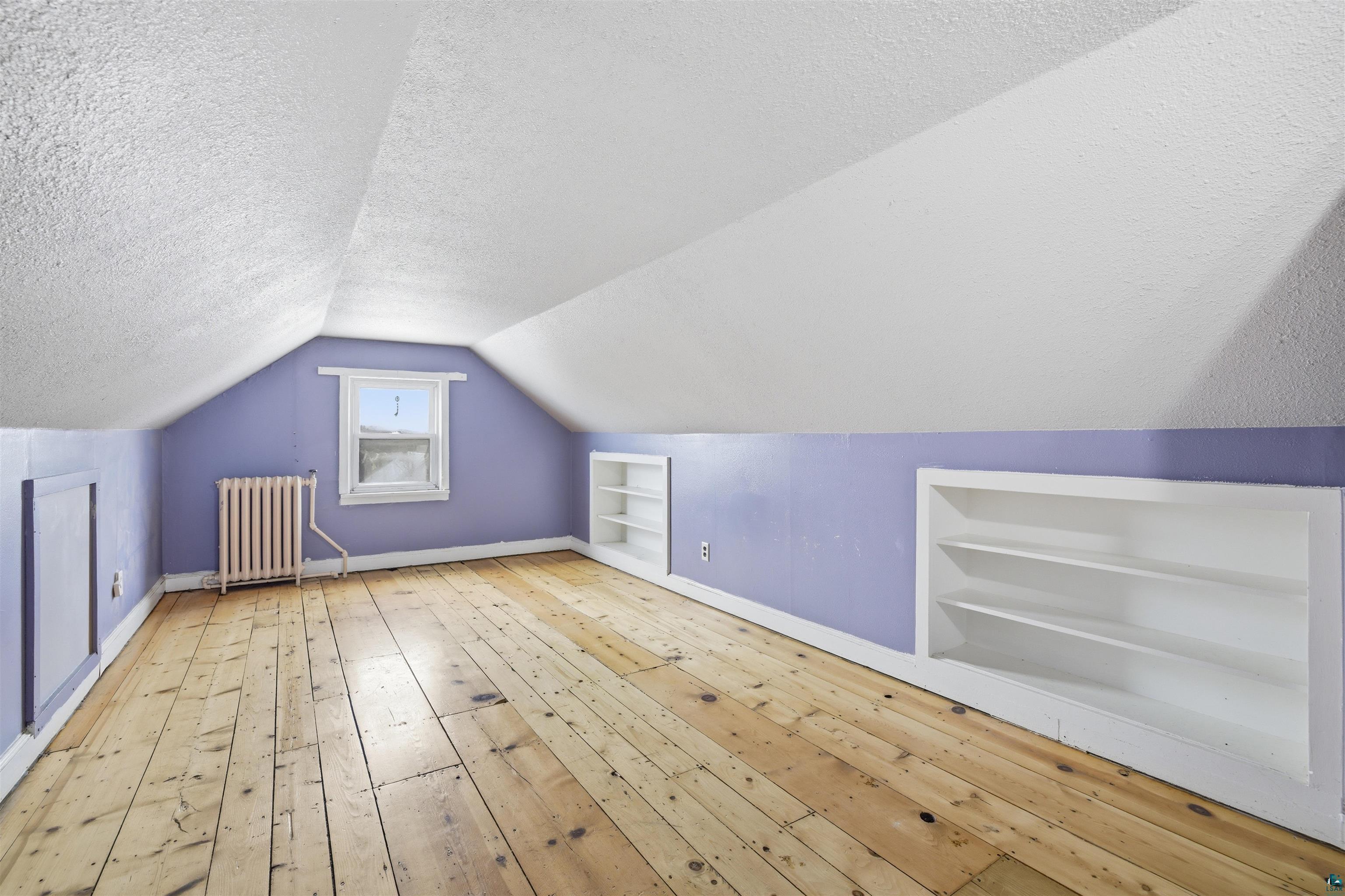 726 Summit Street Eveleth, MN 55734 - Photo 17 of 29 Additional living space with built in shelves, light wood-style flooring, radiator, and a textured ceiling