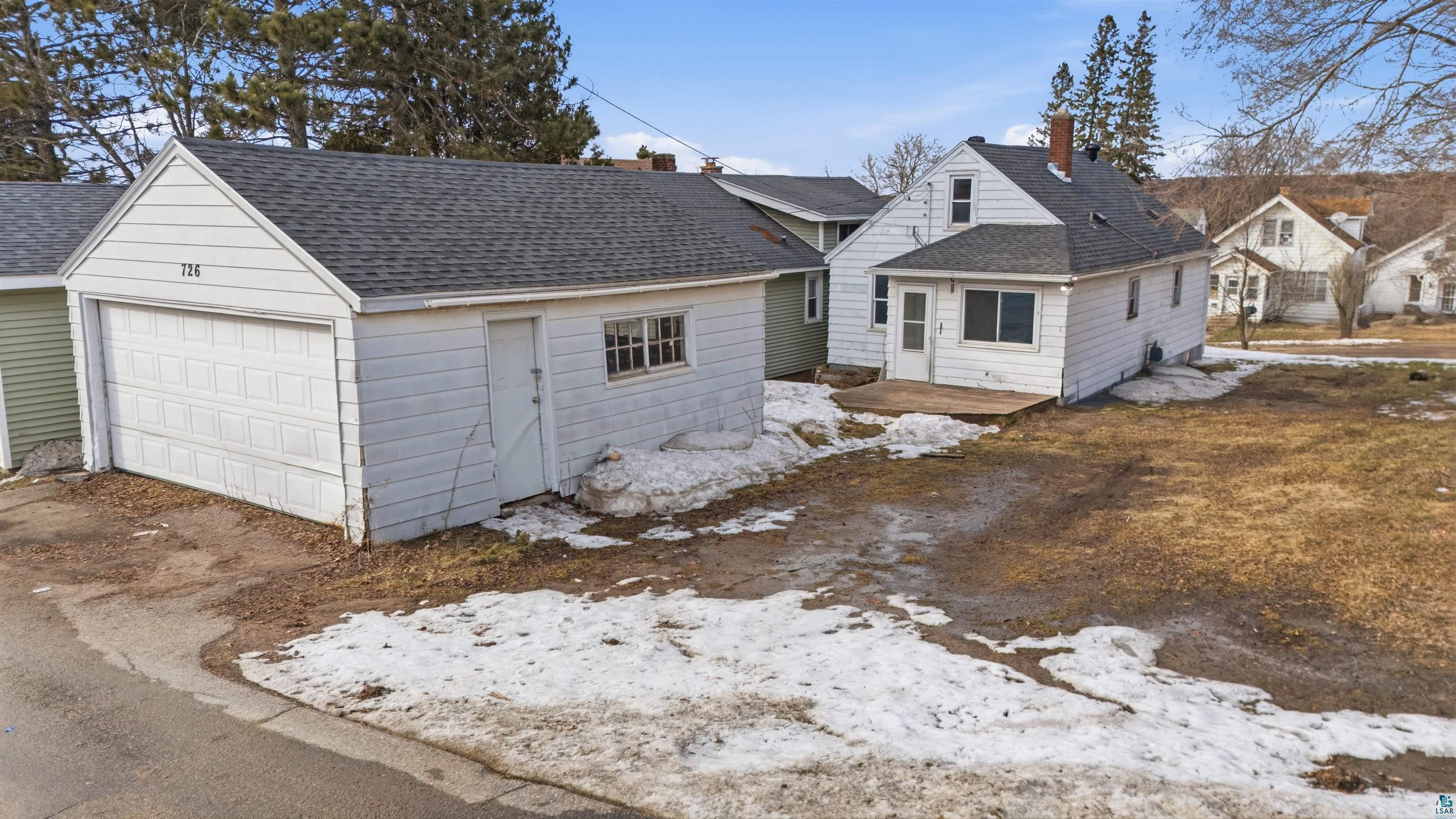 726 Summit Street Eveleth, MN 55734 - Photo 3 of 29 View of front facade with roof with shingles, a garage, an outbuilding, a chimney, and a patio