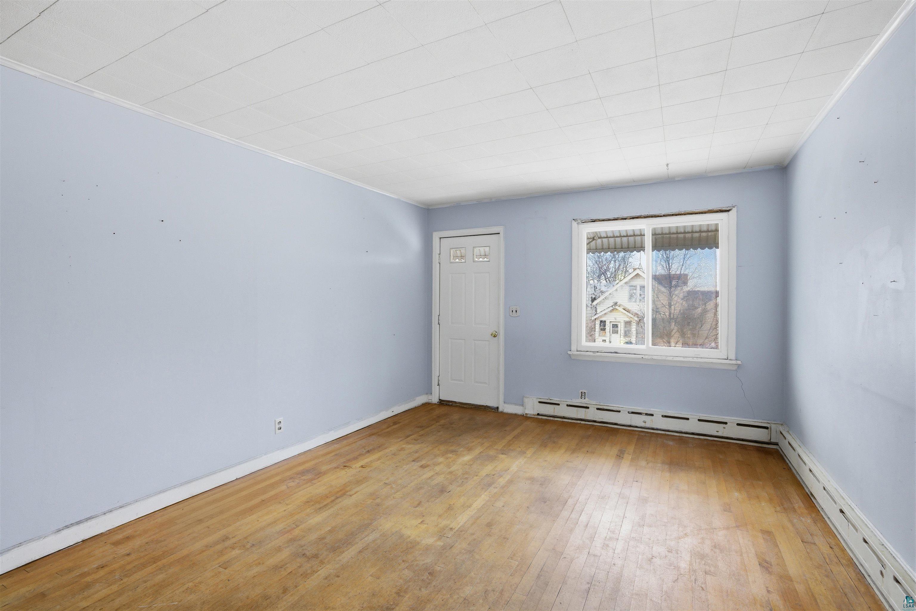 726 Summit Street Eveleth, MN 55734 - Photo 5 of 29 Spare room with light wood-style flooring, baseboard heating, a baseboard heating unit, and crown molding