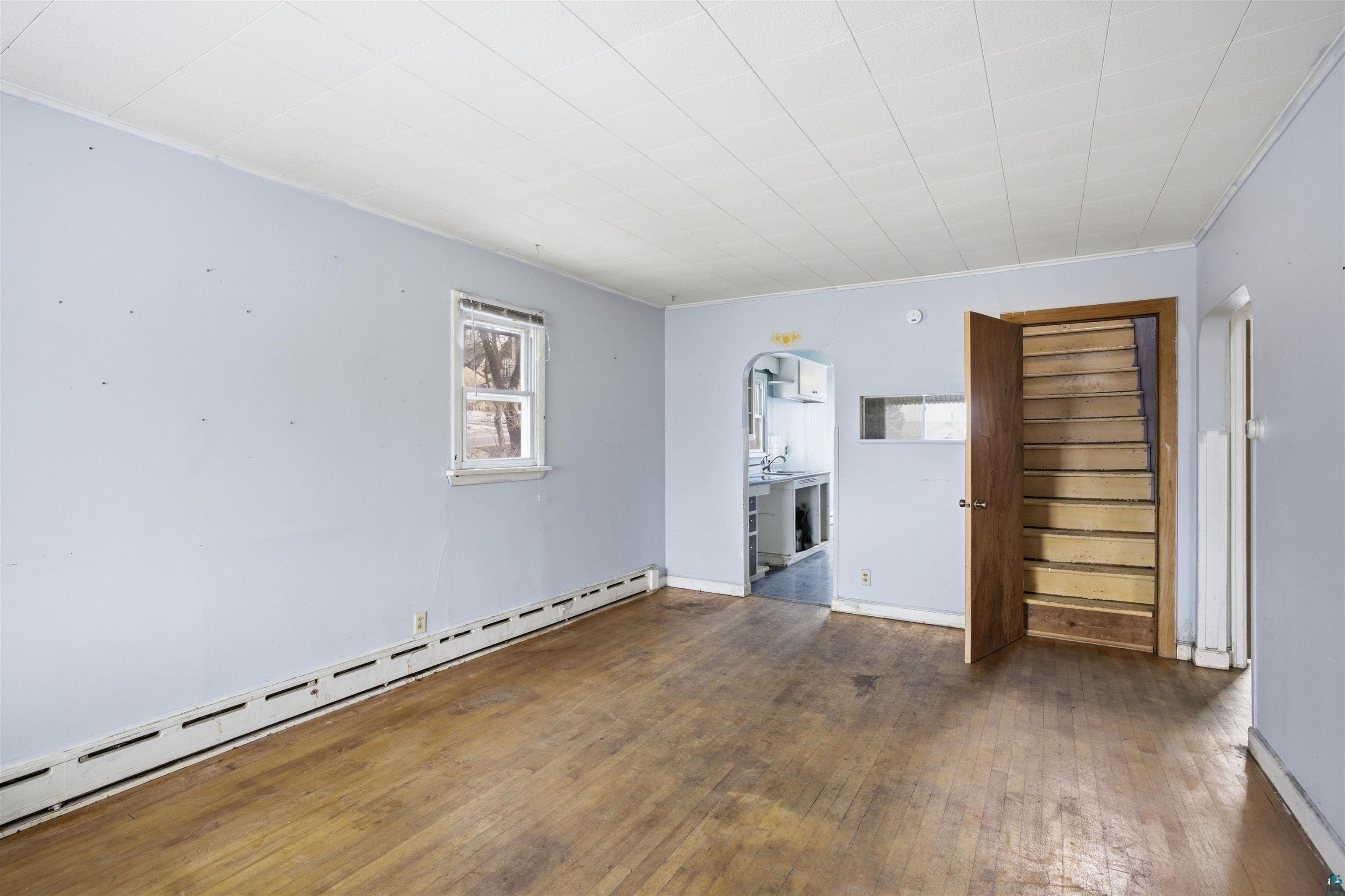 726 Summit Street Eveleth, MN 55734 - Photo 6 of 29 Unfurnished room featuring a baseboard radiator, dark wood-style floors, and ornamental molding