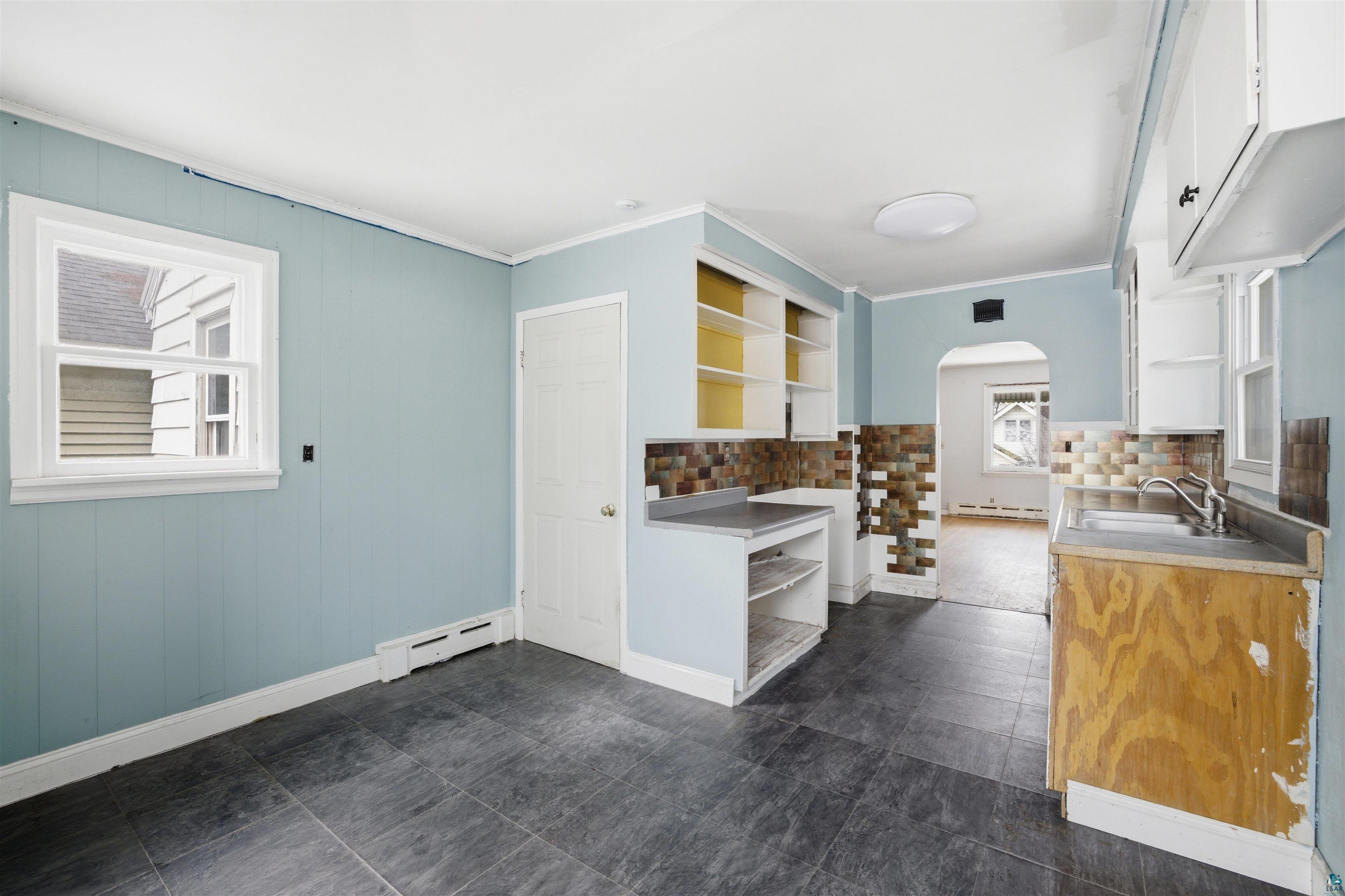 726 Summit Street Eveleth, MN 55734 - Photo 9 of 29 Kitchen featuring open shelves, arched walkways, a baseboard heating unit, light countertops, and backsplash