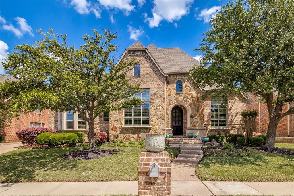 View of front of house with stone siding, a front yard, brick siding, and a shingled roof