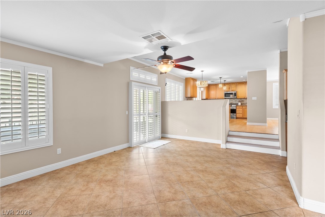 708 Vortex Avenue Henderson, NV 89002 - Photo 20 of 71 A well-lit living area features tiled flooring and white plantation shutters, with a view into the kitchen.