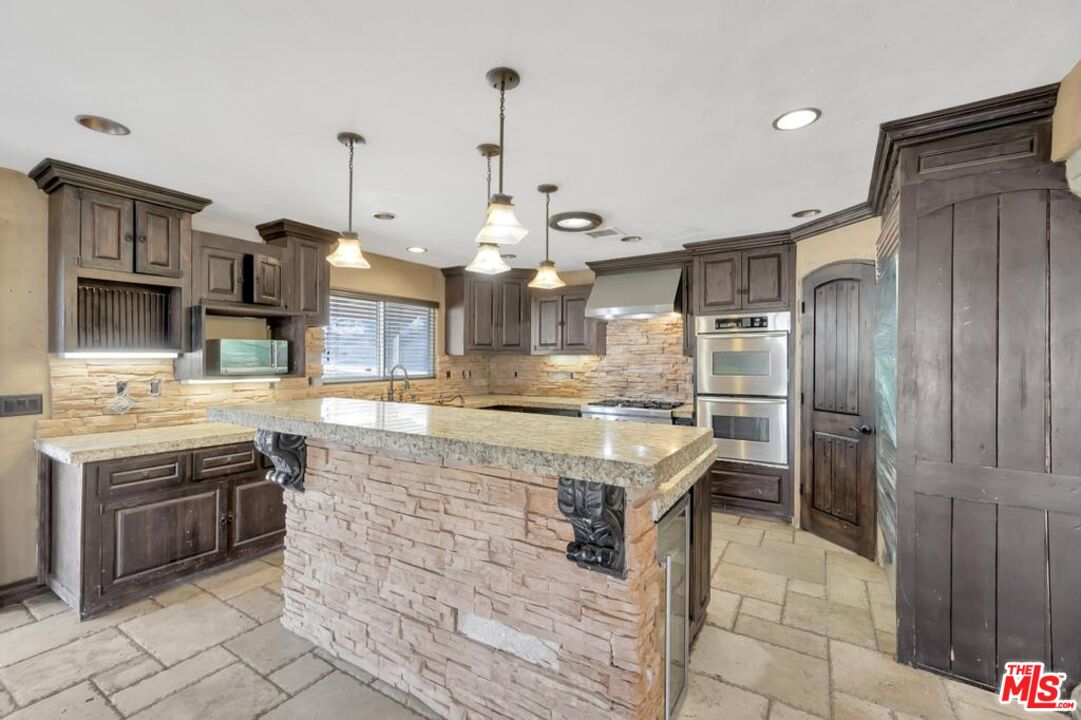 11455 Pigeon Pass Road Moreno Valley, CA 92557 - Photo 26 of 48 a large kitchen with kitchen island a sink stainless steel appliances and cabinets