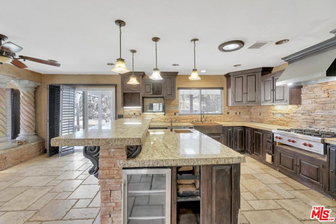 11455 Pigeon Pass Road Moreno Valley, CA 92557 - Photo 27 of 48 a kitchen with granite countertop a stove a sink and a wooden cabinets