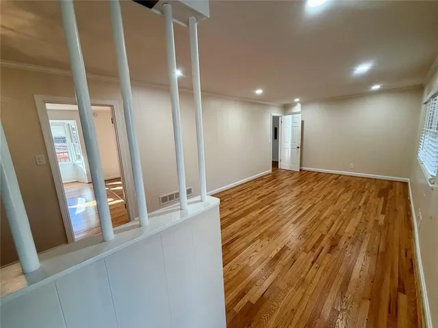 a view of a hallway with wooden floor and staircase