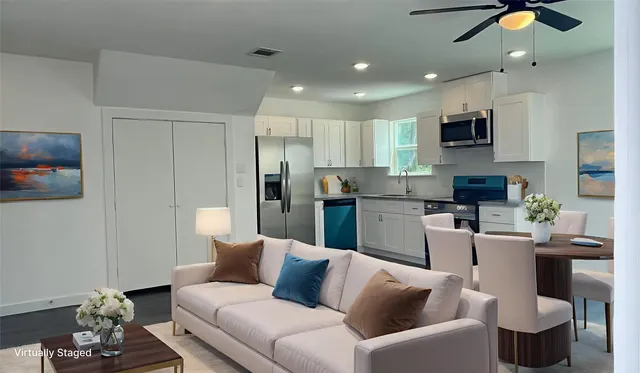 a living room with furniture a flat screen tv and kitchen view
