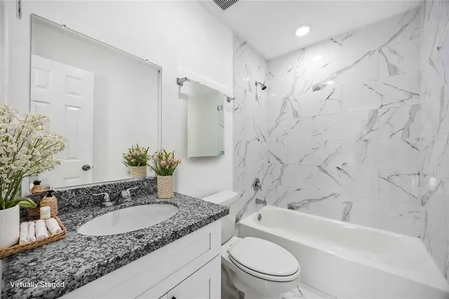 a bathroom with a granite countertop sink a toilet and shower