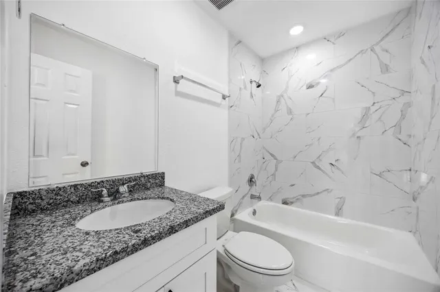 a bathroom with a granite countertop sink toilet and shower