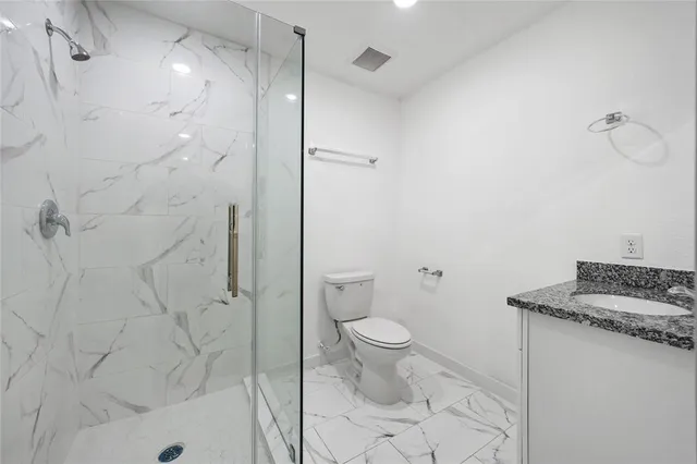 a bathroom with a granite countertop sink a toilet and shower
