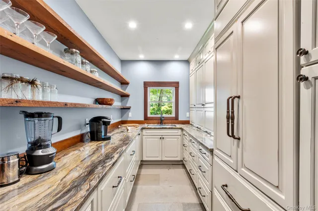 a large white kitchen with a large window a sink and stainless steel appliances