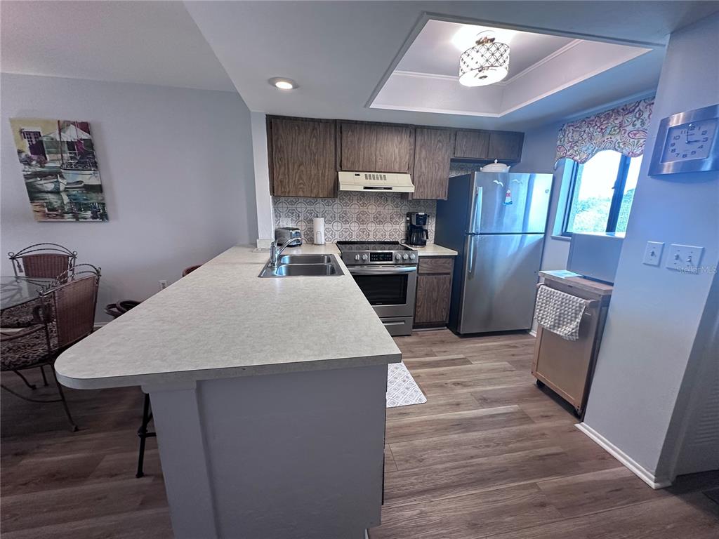 25225 Rampart Boulevard, Unit 105 Punta Gorda, FL 33983 - Photo 17 of 40 a kitchen with stainless steel appliances a table chairs refrigerator and wooden floor