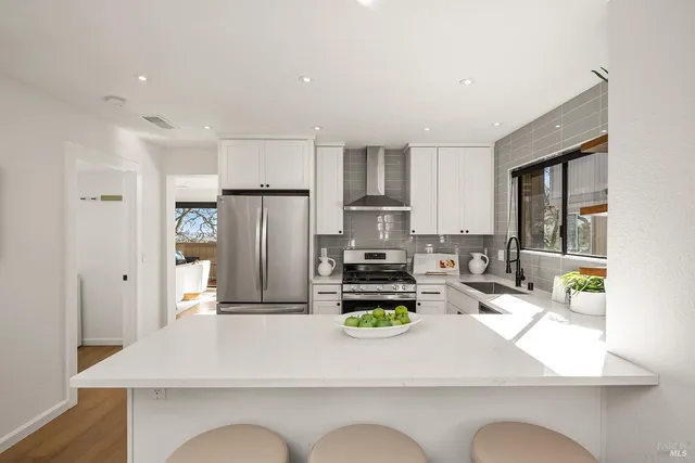 a kitchen with a refrigerator a stove a sink dishwasher with a dining table and chairs