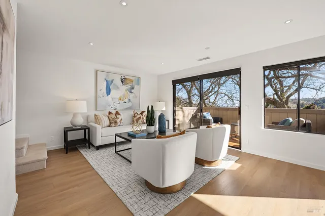 a living room with couches a coffee table and painting on the wall with a large window