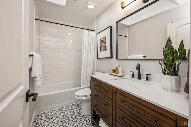 a bathroom with a granite countertop sink a toilet and shower