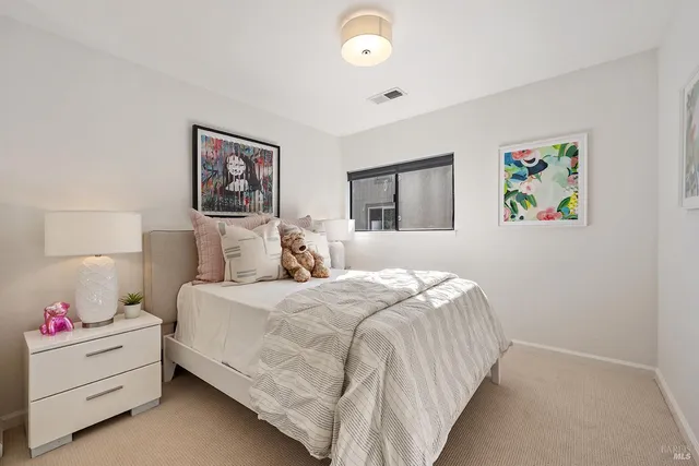 a bedroom with a bed and a lamp on dresser