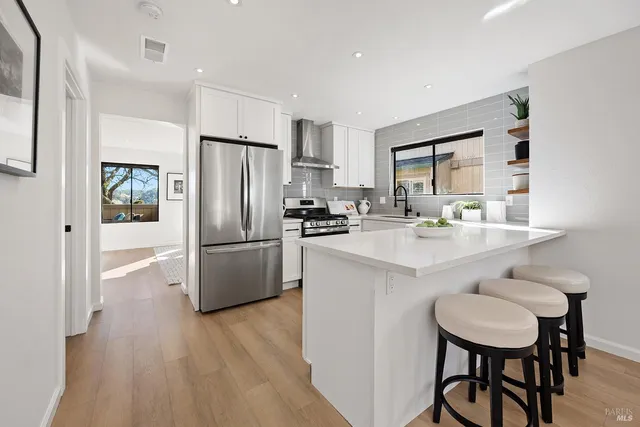 a kitchen with stainless steel appliances a refrigerator a sink a stove a dining table and chairs